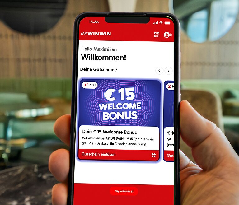 Es ist ein Handy zu sehen, auf dem der Startbonus in der MYWINWIN Applikation gezeigt wird. 